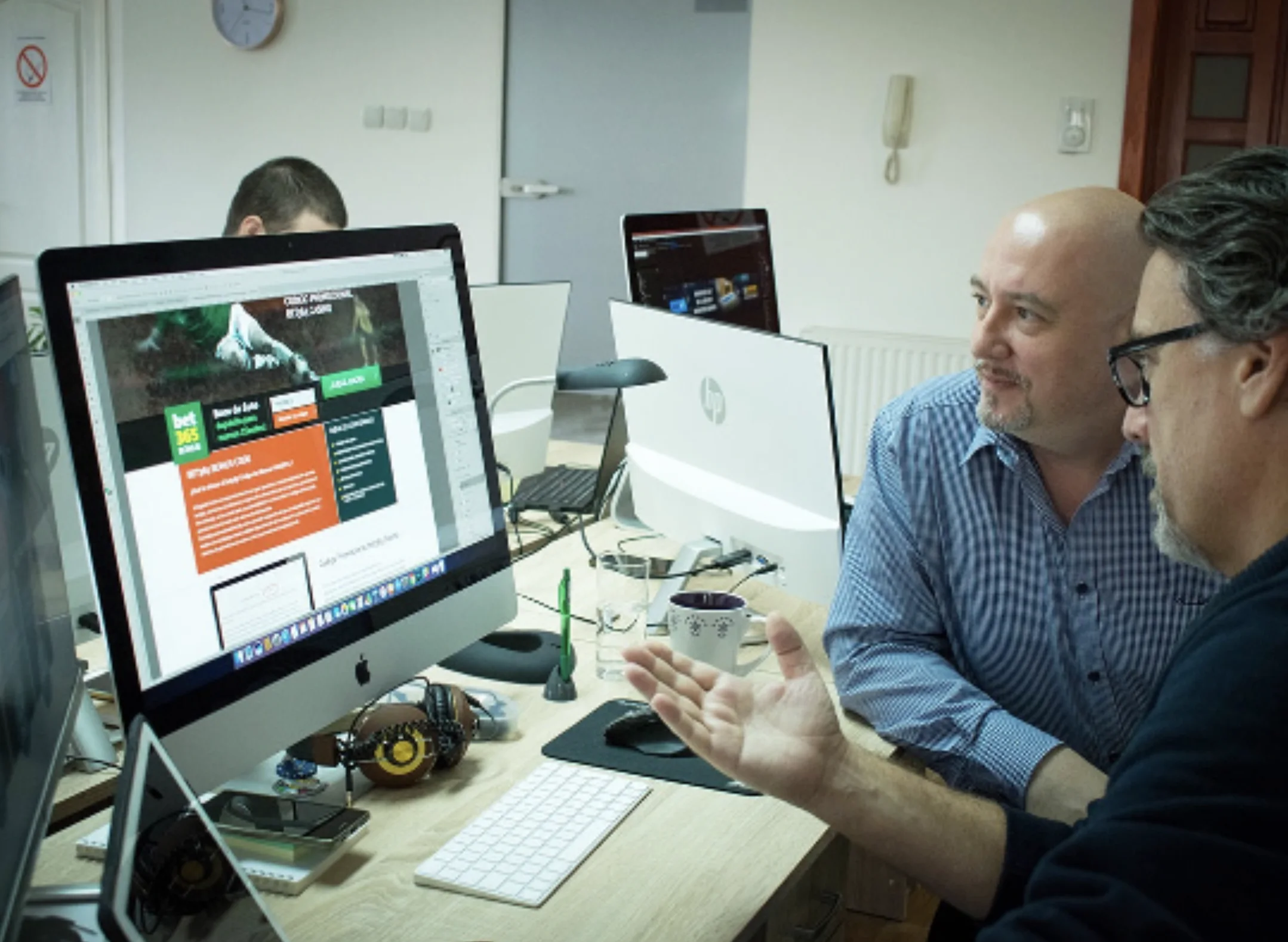 Colleagues reviewing a website design together at a desktop computer.